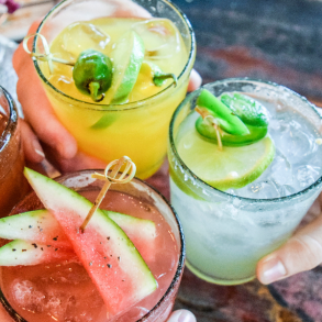 people clinking fruity cocktail drinks