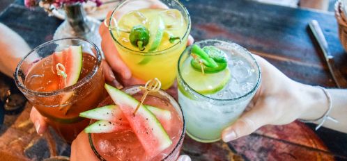 people clinking fruity cocktail drinks