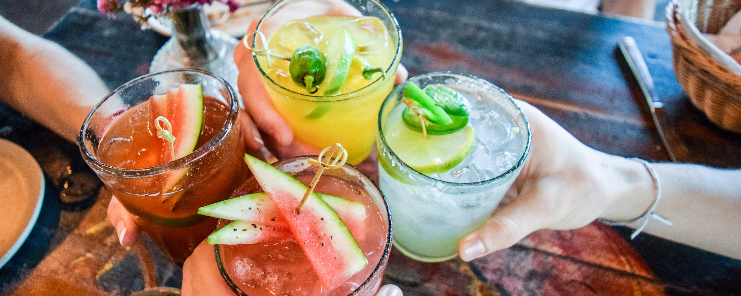 people clinking fruity cocktail drinks