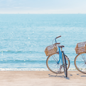 two blue bikes with baskets on beach