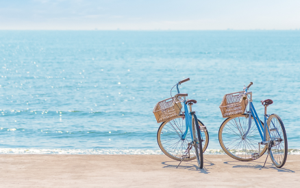 two blue bikes with baskets on beach