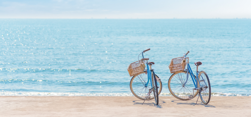 two blue bikes with baskets on beach