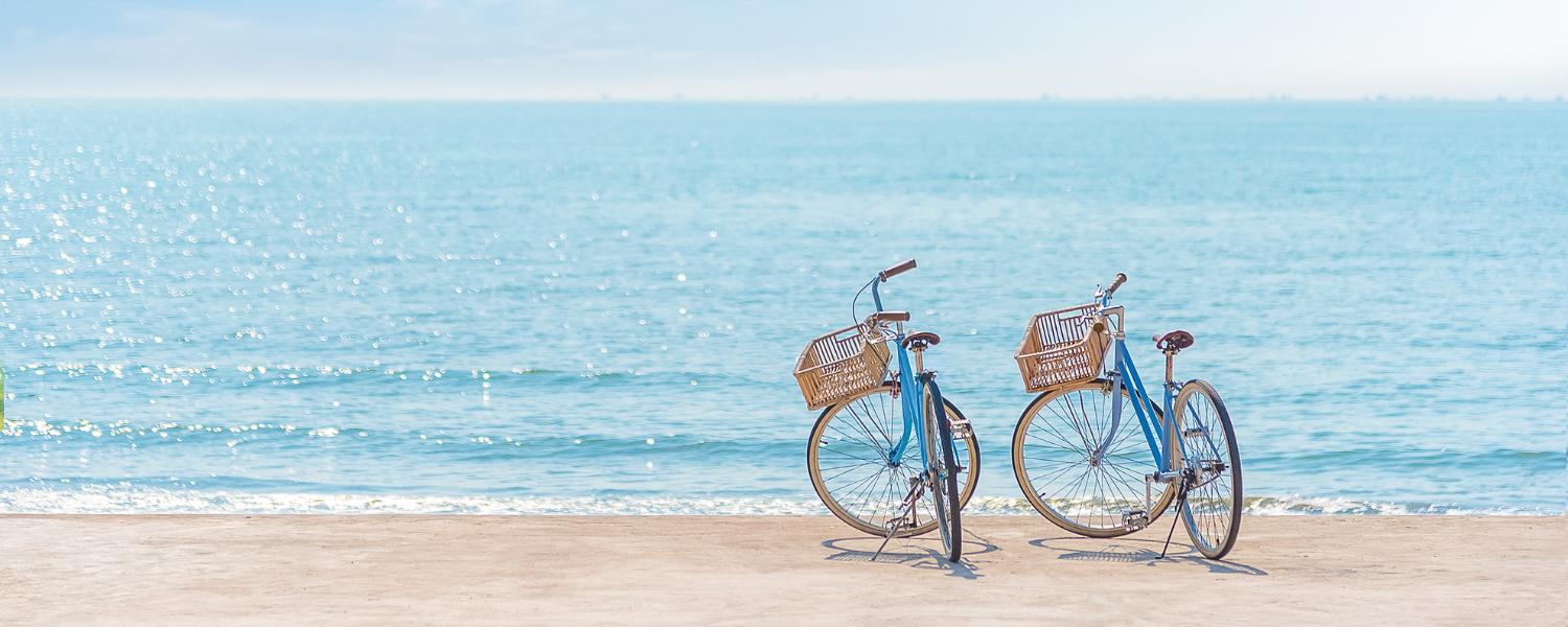 two blue bikes with baskets on beach