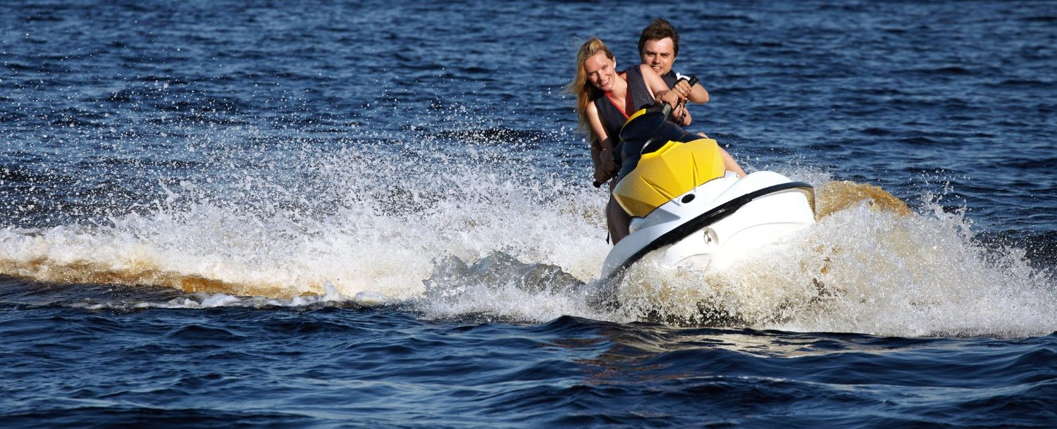 Happy couple riding a jet ski in the ocean