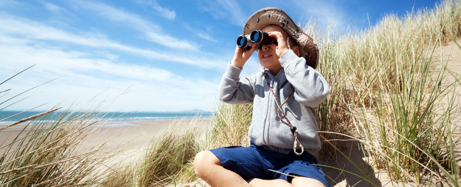 Little boy searching with binoculars at the beach on an eco tour on the isle of palms