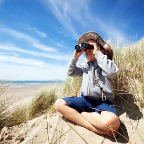 Little boy searching with binoculars at the beach on an eco tour on the isle of palms