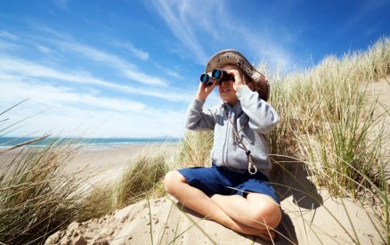Little boy searching with binoculars at the beach on an eco tour on the isle of palms