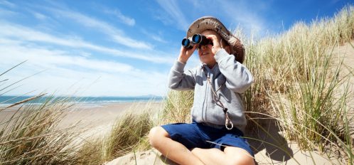 Little boy searching with binoculars at the beach on an eco tour on the isle of palms