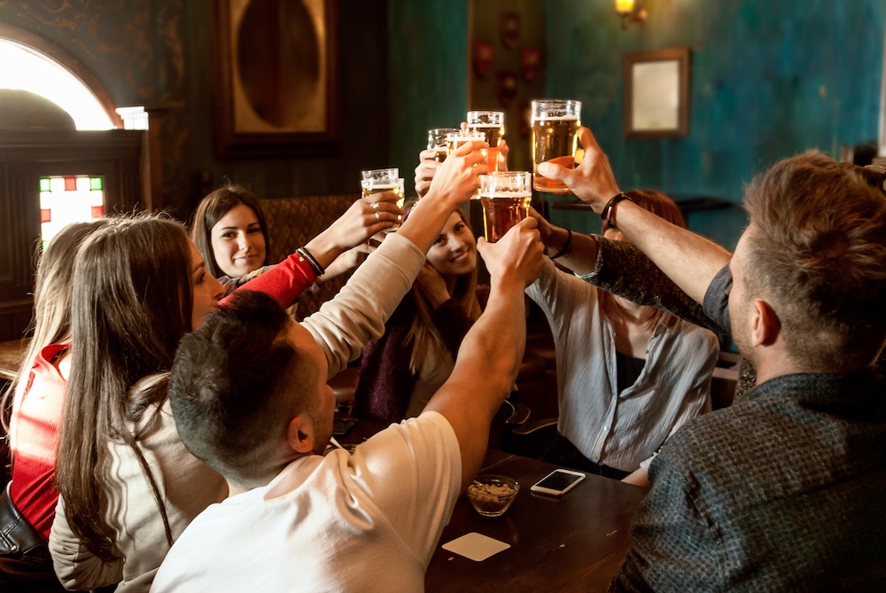 A group of people celebrating in a pub, drinking beer.