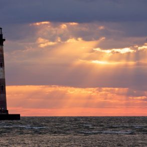 Morris Island Lighthouse with the sun peaking through clouds