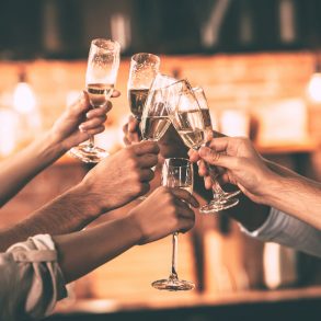 Group of people cheering with champagne flutes with home interior in the background