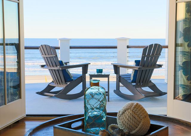   two beach chairs on a deck overlooking the ocean