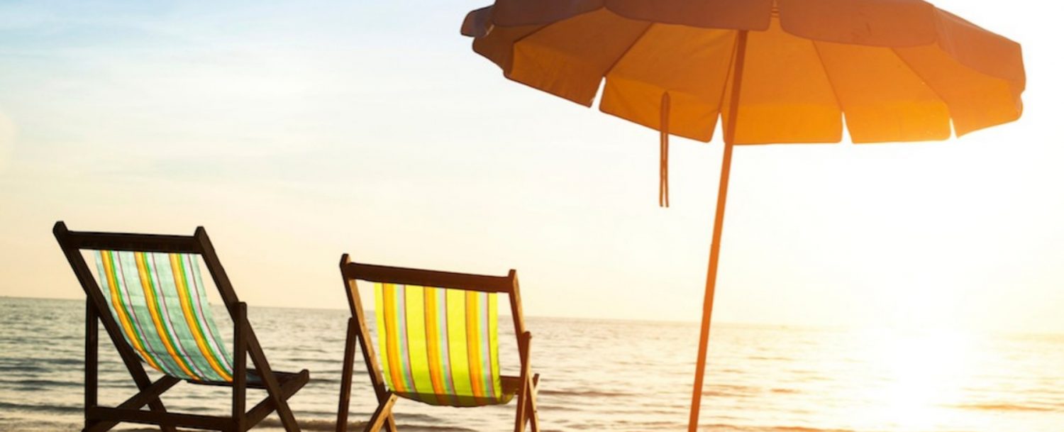 Beach chairs and an umbrella on the beach during sunrise