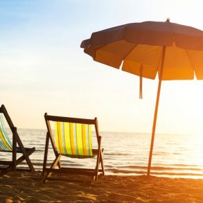 Beach chairs and an umbrella on the beach during sunrise