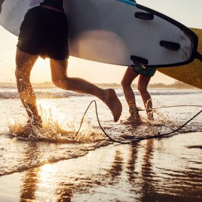 two people with surfboards running into the ocean