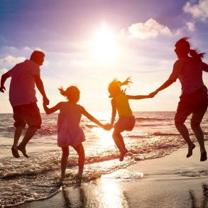 a family jumping up and down on the beach in the surf