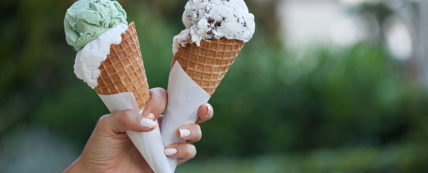 a person holding two ice cream cones