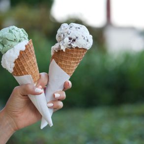 a person holding two ice cream cones