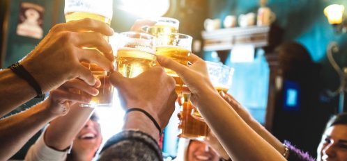 People toasting cups of beer at a brewery.