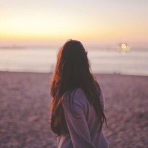 Woman walking on the beach at sunset.