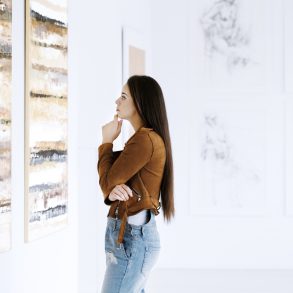 Young woman observing painting while visiting art gallery with famous artist collection