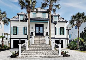 Large white house with black accents and stairs leading up to doors on a beautiful sunny day on IOP