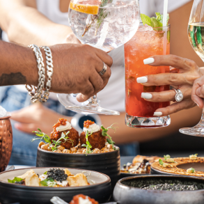people toasting with cocktails over food