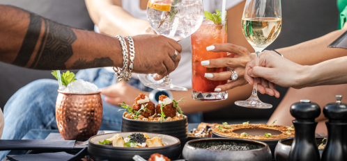 people toasting with cocktails over food