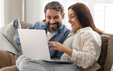 couple sitting on couch looking at computer