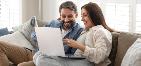 couple sitting on couch looking at computer