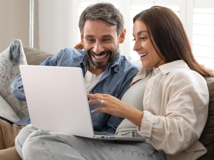 couple sitting on couch looking at computer