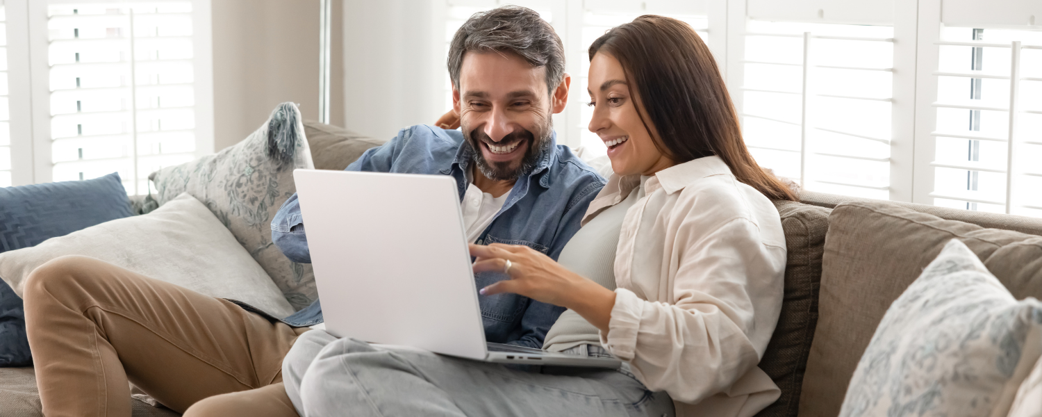 couple sitting on couch looking at computer