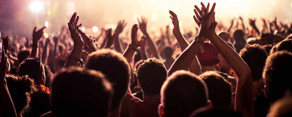 Audience with their hands in the air at a music festival.