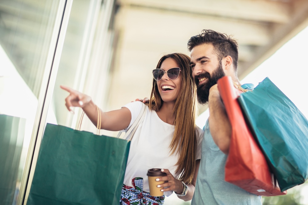 Beautiful couple enjoy shopping together, young couple holding shopping bags.